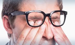 Man with glasses rubbing eyes